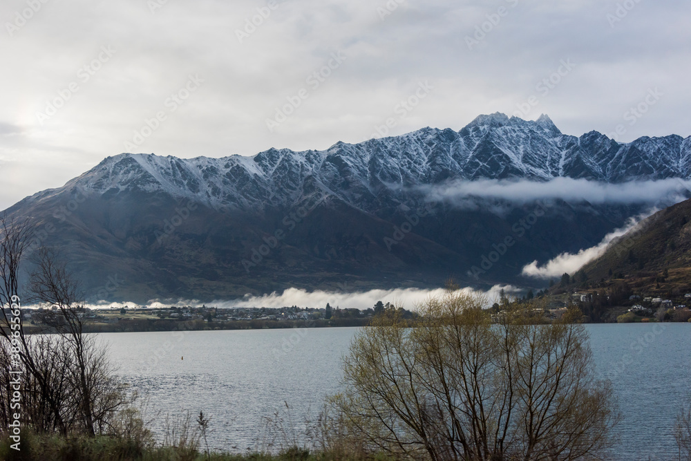 湖の対岸に冠雪した山脈と朝靄