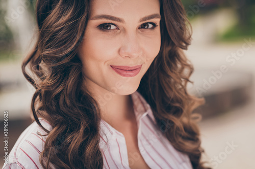 Cropped close-up of beautiful young girl with curly brunette hair smiling wearing white casual shirt walking on the street