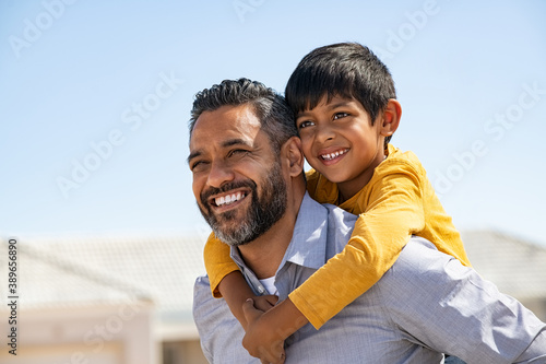 Fotografie, Obraz Happy smiling indian father giving son ride on back