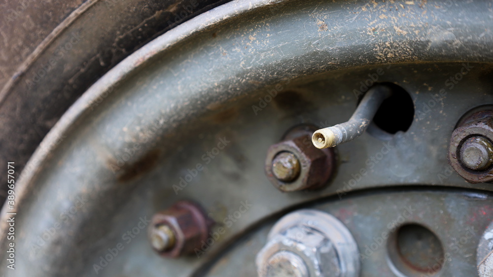Close up of the nipple without the cap of the car wheels. On the background of the rims and large truck tires with a copy area. Close focus and select an object