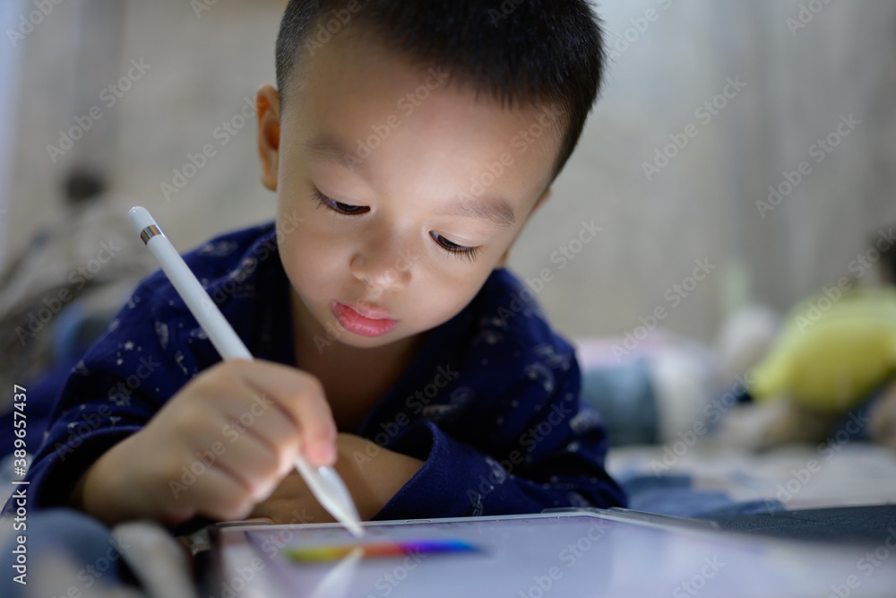 child drawing on tablet screen with white pencil. The boy paints a picture on the touchscreen of new tablet. baby boy playing games on personal tablet. Kid learning art child drawing on tablet screen with white pencil. The boy paints a picture on the touchscreen of new tablet. baby boy playing games on personal tablet. Kid learning art