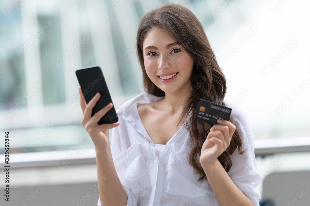 Black Friday concept, Woman holding phone with credit card and smiling near the store Black Friday concept, Woman holding phone with credit card and smiling near the store