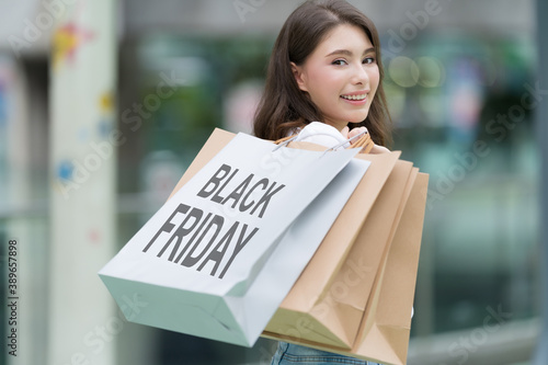 Black Friday concept, Woman holding many shopping bags and smiling in the store during shopping process