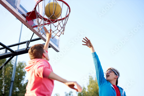teens boys shooting basket and playing basketball at playground, lower view wide angle