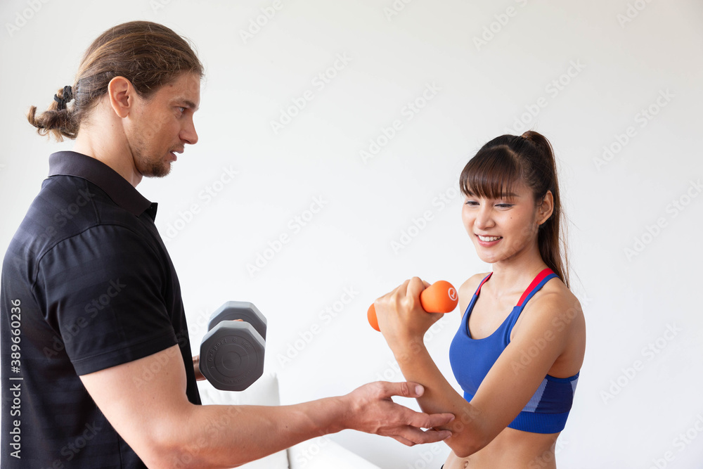 Sporty girl having weight exercise with assistance from her personal trainer at home Sporty girl having weight exercise with assistance from her personal trainer at home