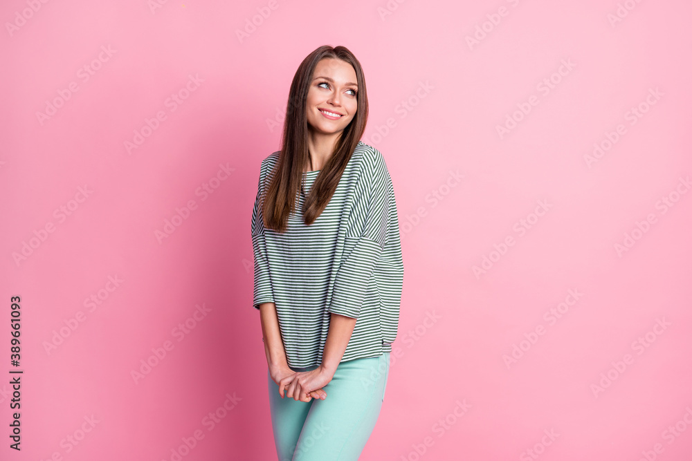 Photo of young girl look empty space hold arms wear striped shirt teal pants isolated pastel pink color background Photo of young girl look empty space hold arms wear striped shirt teal pants isolated pastel pink color background