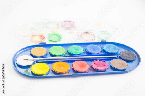 Side view of watercolor paint palette with brush inside on white background