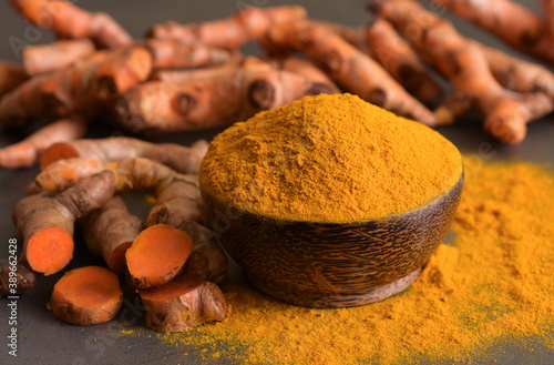 Turmeric powder and fresh turmeric (curcumin) on black background,For cooking and as an herbal medicine. © natthapol