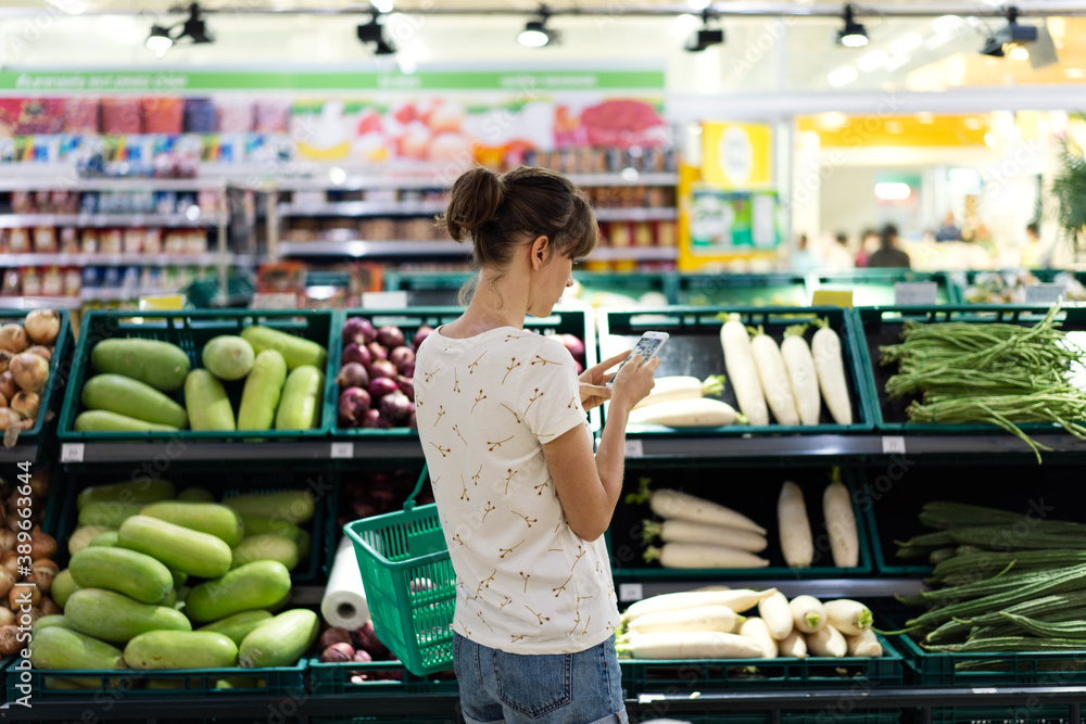 Woman using mobile phone while shopping in supermarket