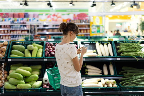 Obraz na płótnie Woman using mobile phone while shopping in supermarket w salonie