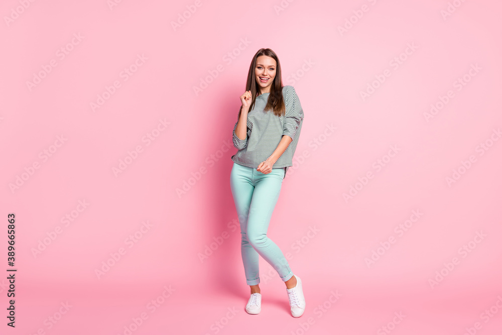 Full size photo of optimistic nice woman dancing wear shirt blue pants white sneakers isolated on pastel pink color background Full size photo of optimistic nice woman dancing wear shirt blue pants white sneakers isolated on pastel pink color background