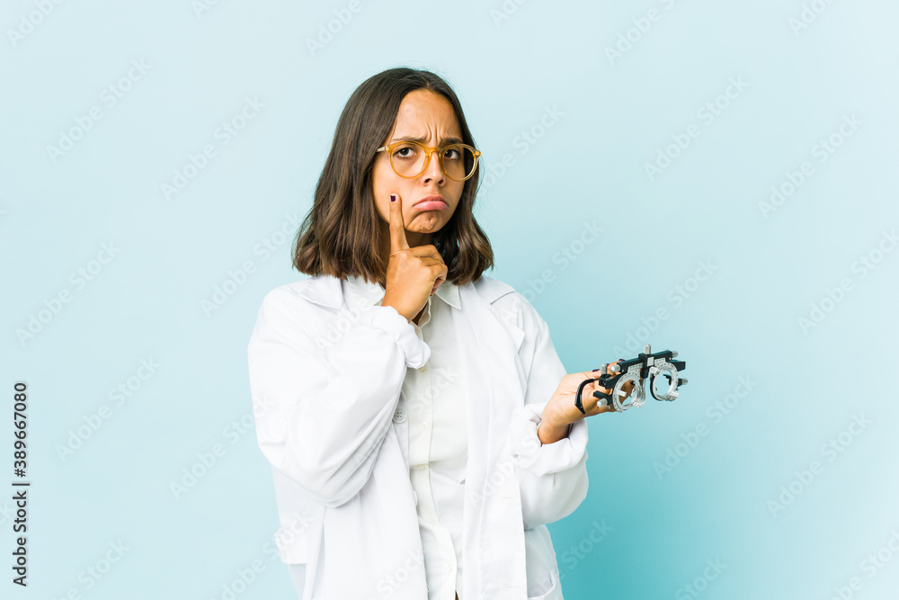 Young oculist latin woman over isolated background Young oculist latin woman over isolated background