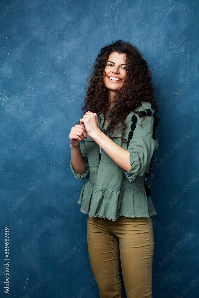 young pretty woman with curly brunette hair posing cheerful on blue background, lifestyle people concept young pretty woman with curly brunette hair posing cheerful on blue background, lifestyle people concept