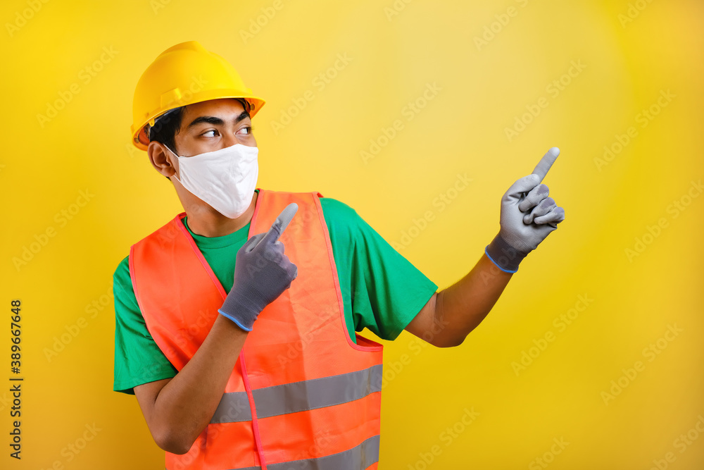 Asian construction worker wearing protective mask pointing isomething in his side