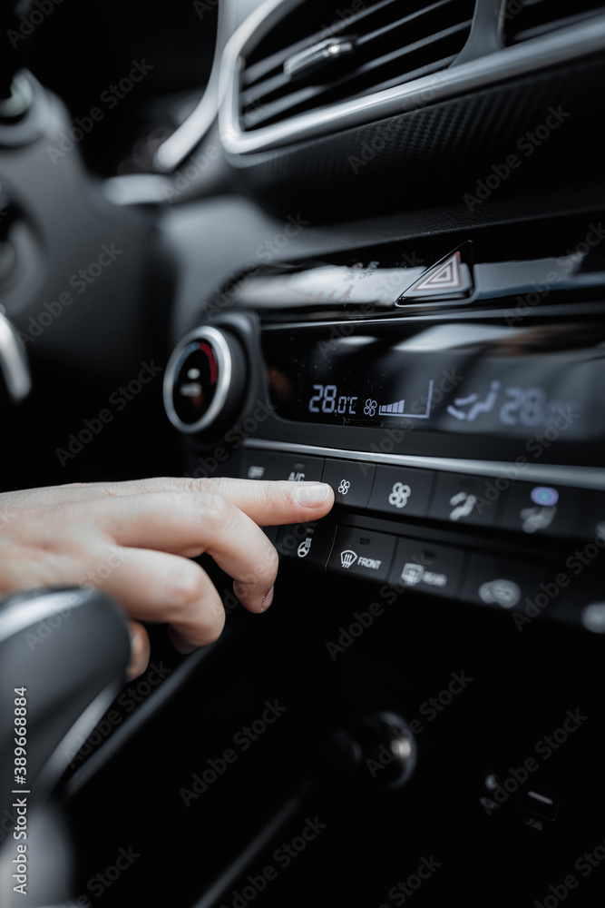 Interior view of a new car. Climate or air conditioner system adjusted by a woman. Adjusting temperature of car's interior