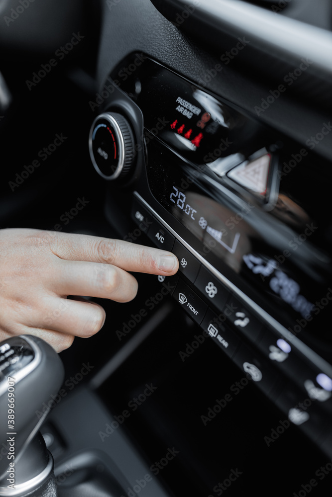 Interior view of a new car. Climate or air conditioner system adjusted by a woman. Adjusting temperature of car's interior