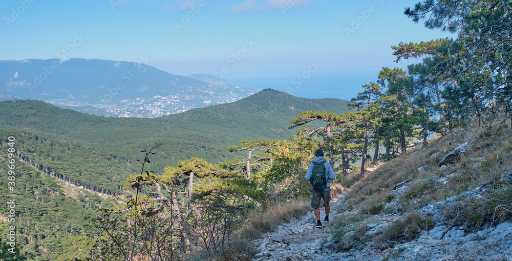 the southern Crimea. Scenic slope of Ai Petri mountain. A man with a backpack is walking along the rocky mountain trail.