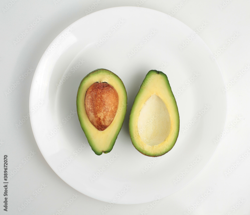 Two slices of avocado on a plate on a white background.Top view