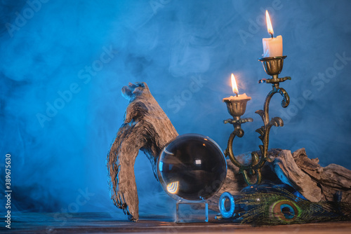 Crystal ball and burning candle on the table in the smoke.