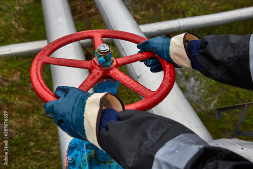 Technician, hands in rubber gloves while opening or closing a manual ball valve for the control process on an offshore oil and gas platform photo