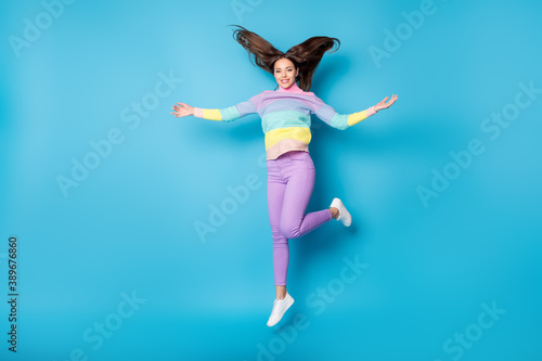 Full length body size view of pretty sthin careless funky cheerful girl jumping having fun throwing hair isolated on bright blue color background