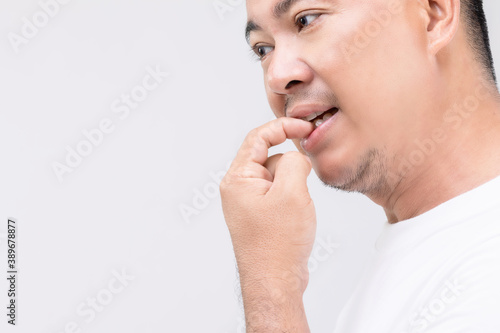 Nail Biting (Onychophagia) concept : Portrait people biting his nail. Studio shot isolated on grey