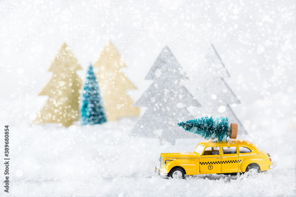 Toy car carrying christmas tree in a snow forest