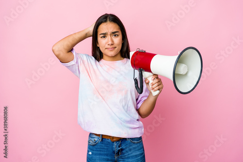 Young asian woman holding a megaphone isolated on pink background being shocked, she has remembered important meeting.
