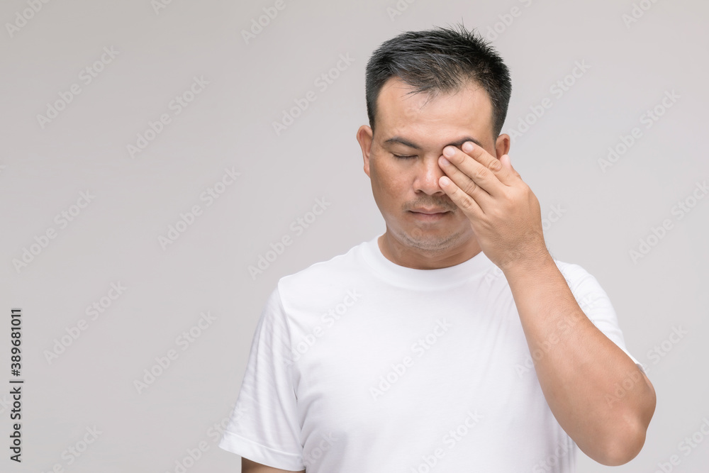 Eye irritation concept : Portrait of Asian man in posture of eye tired, irritation or problem about his eye. Studio shot isolated on grey Eye irritation concept : Portrait of Asian man in posture of eye tired, irritation or problem about his eye. Studio shot isolated on grey