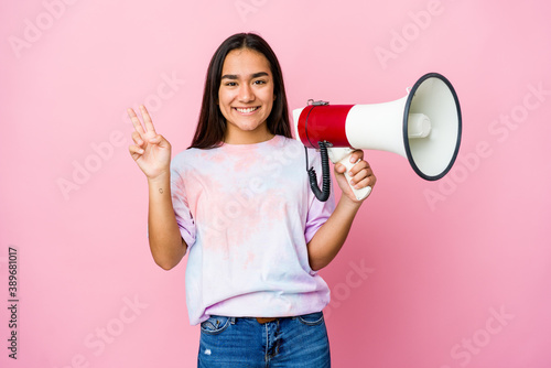 Young asian woman holding a megaphone isolated on pink background showing number two with fingers.