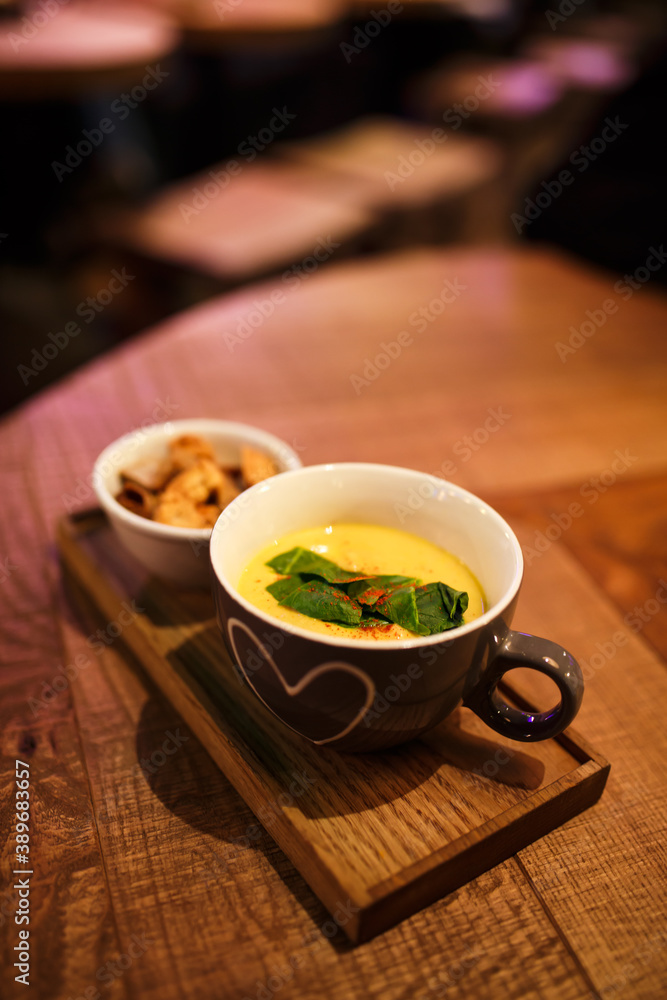 Serving cream soup in a cup with a cup of rusks on a wooden tray Serving cream soup in a cup with a cup of rusks on a wooden tray