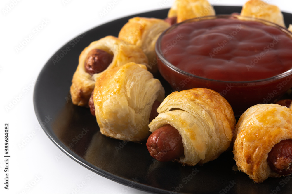 Pigs in blankets. Mini sausages wrapped in puff pastry with ketchup sauce isolated on white background Pigs in blankets. Mini sausages wrapped in puff pastry with ketchup sauce isolated on white background