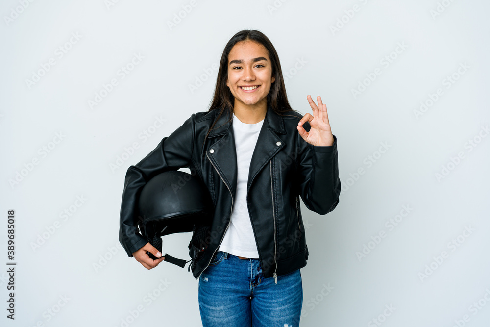 Young asian woman holding a motorbike helmet over isolated background cheerful and confident showing ok gesture. Young asian woman holding a motorbike helmet over isolated background cheerful and confident showing ok gesture.