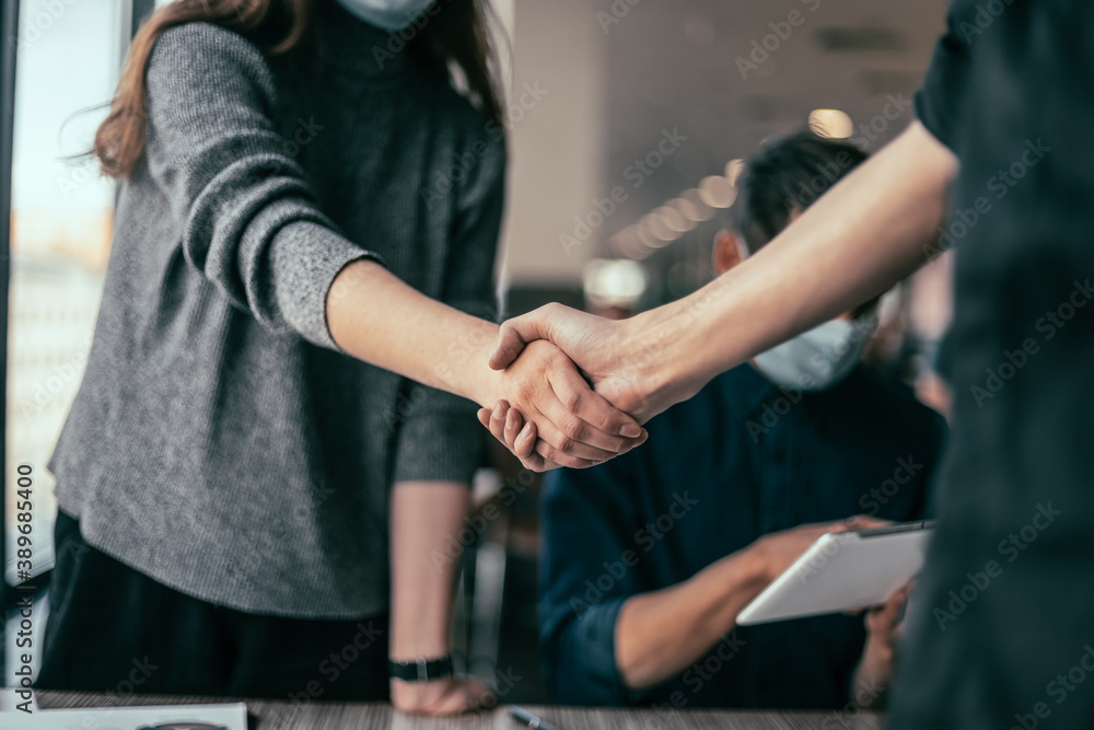 young staff in protective masks shaking hands with each other. young staff in protective masks shaking hands with each other.