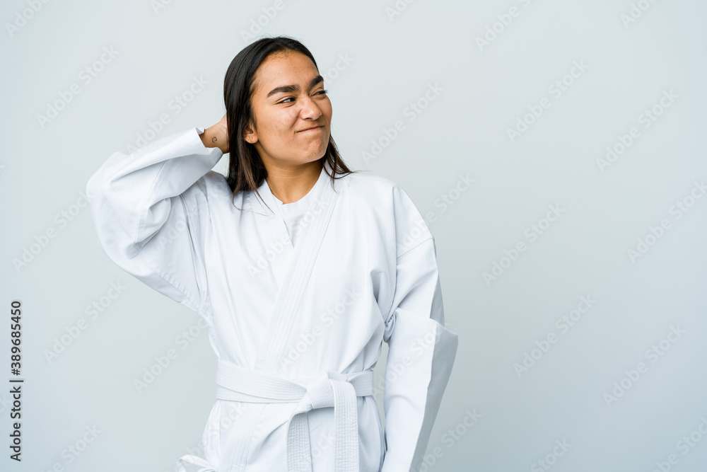 Young asian woman doing karate isolated on white background touching back of head, thinking and making a choice.