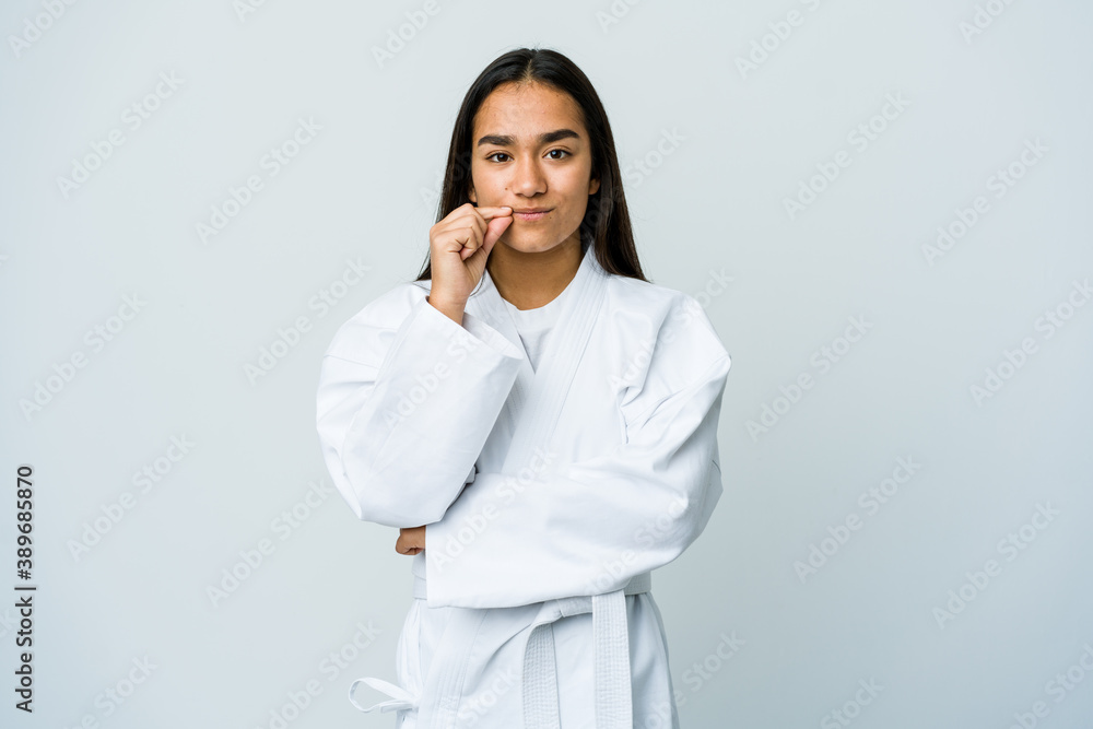 Young asian woman doing karate isolated on white background with fingers on lips keeping a secret. Young asian woman doing karate isolated on white background with fingers on lips keeping a secret.