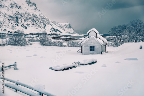 Dramatic morning scene after huge snowfall over polar circle. Snowy winter scene of Lofoten Islands. Small cemetery on Vestvagoy island, Norway, Europe. Vintage filtered.