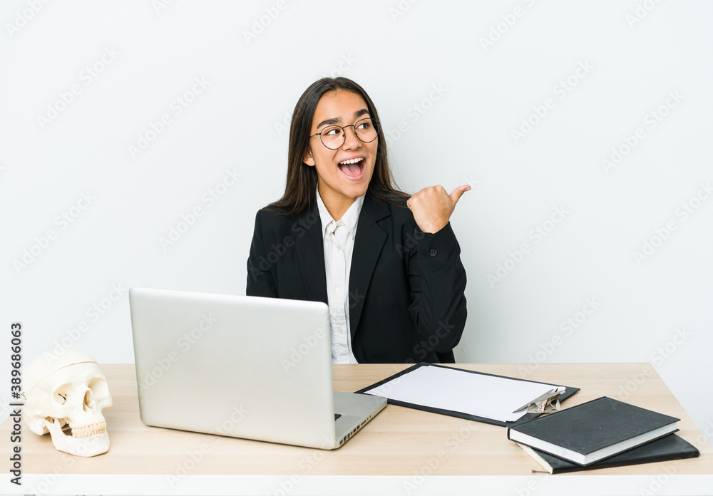 Young traumatologist asian woman isolated on white background points with thumb finger away, laughing and carefree. Young traumatologist asian woman isolated on white background points with thumb finger away, laughing and carefree.