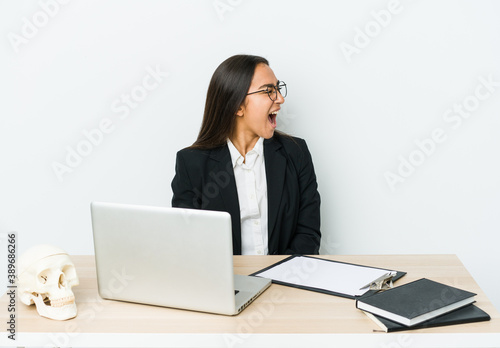 Young traumatologist asian woman isolated on white background shouting towards a copy space