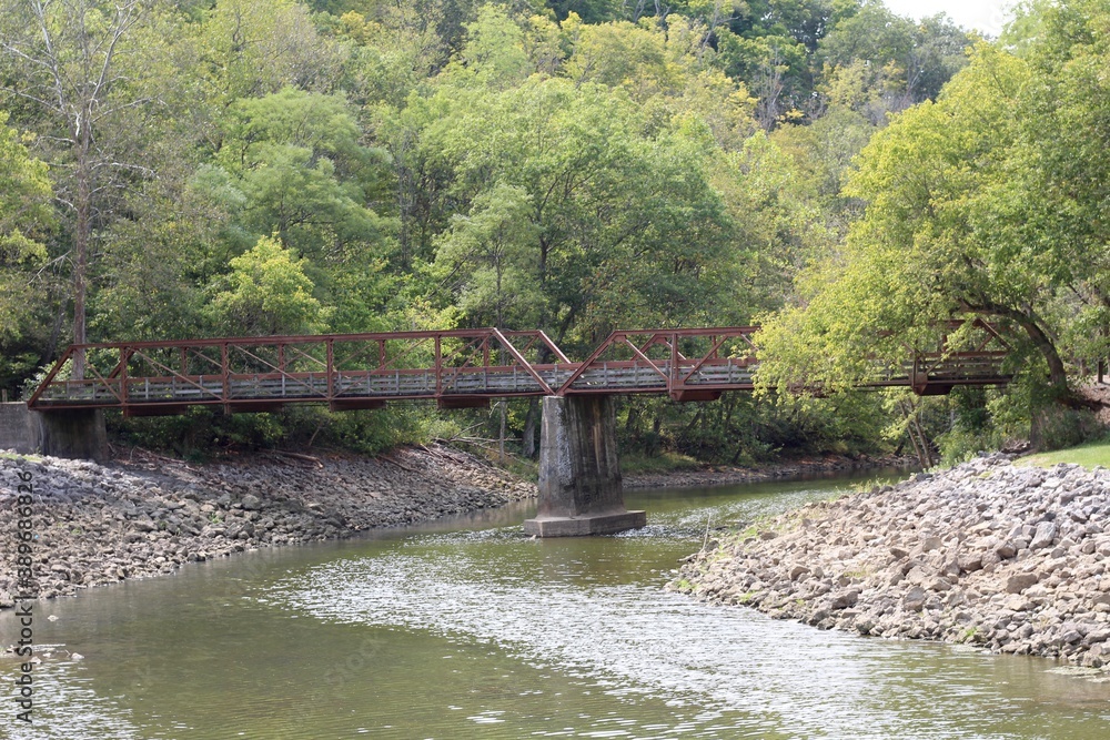 Obraz premium The bridge over the creek in the park on a sunny day.