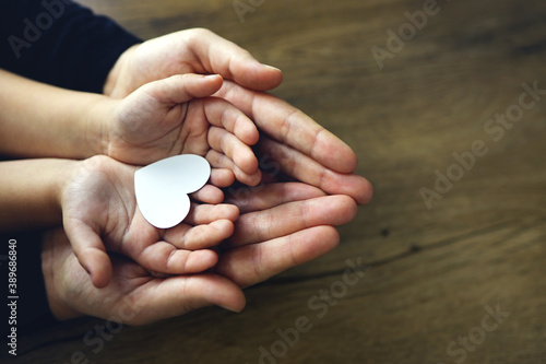 White paper heart in child's and female palms, top view. Love, Mother's day, family concept