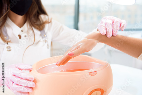Photo process paraffin treatment of female hands in beauty salon