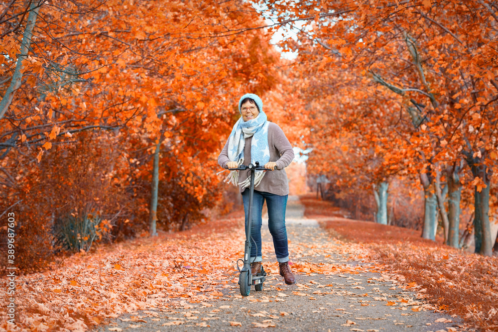 Obraz premium Frau mit Roller in der Herbstallee
