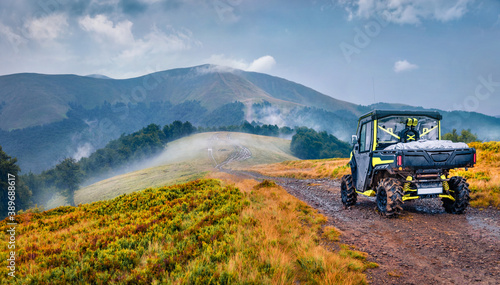 Traveling by all-terrain vehicle on the mountains. Off-road tour in Carpathian mountains, Ukraine, Europe. Foggy summer view of Krasna range. Traveling concept background..