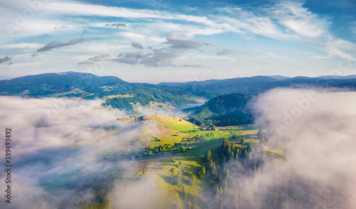 View from flying drone of Carpathian mountains with huge fog spreds on the valley, Ukraine, Europe. Splendid morning scene of Stebnyi village. Traveling concept background.
