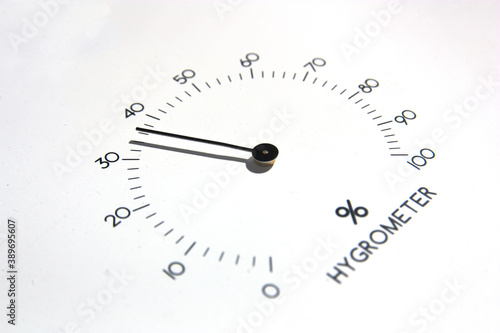 Closeup of the needles of an analog hygrometer on white