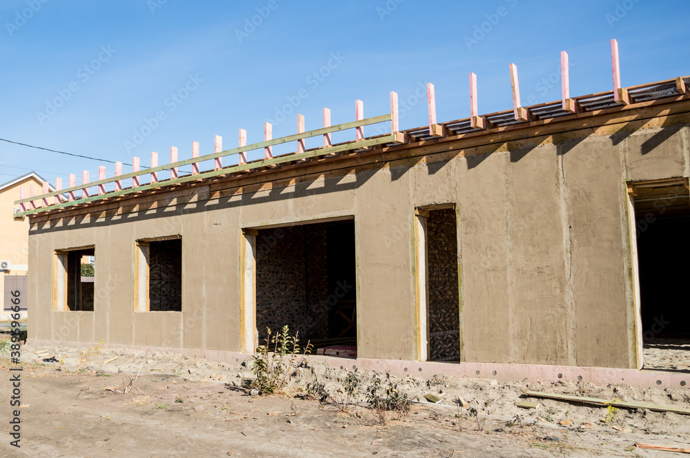 Obraz premium Construction of a house from an environmentally friendly material of plant origin. Frame made of wood, blocks of straw, clay plaster.