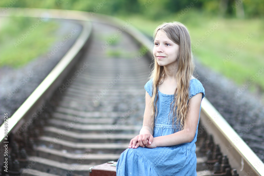 young girl with a suitcase on railway