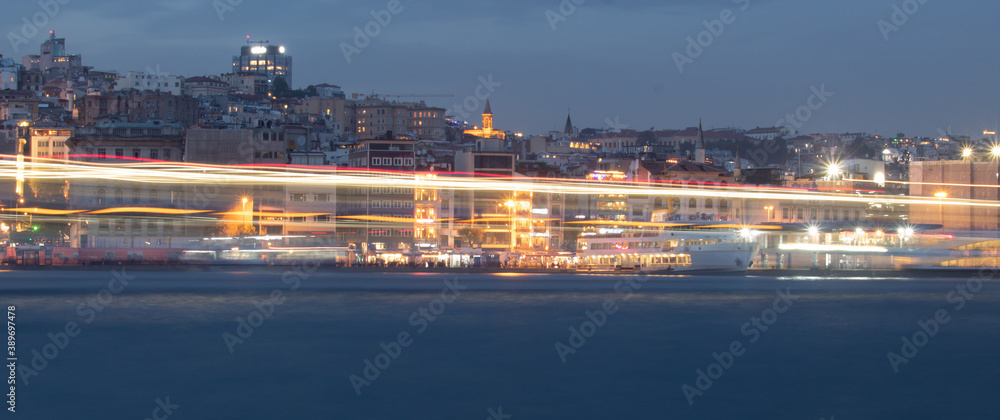 Glowing Trail from ships passing along the Bosphorus against the background of the Istanbul panorama in the evening