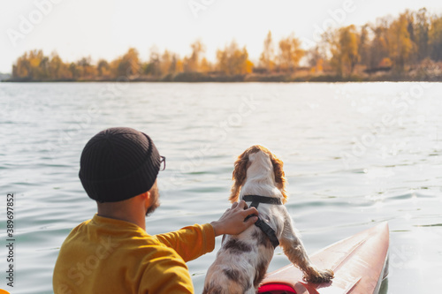 Kayaking with dogs: man sits in a row boat on the lake next to his spaniel. Active rest and adventures with pets, riding a canoe with dog